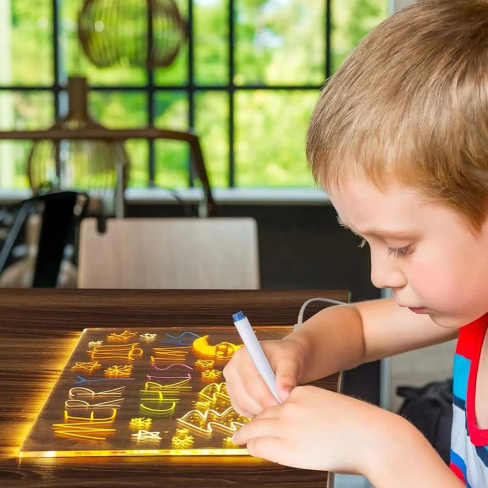 Niño utilizando la tableta LED iluminada para trazar dibujos y practicar letras con rotuladores borrables