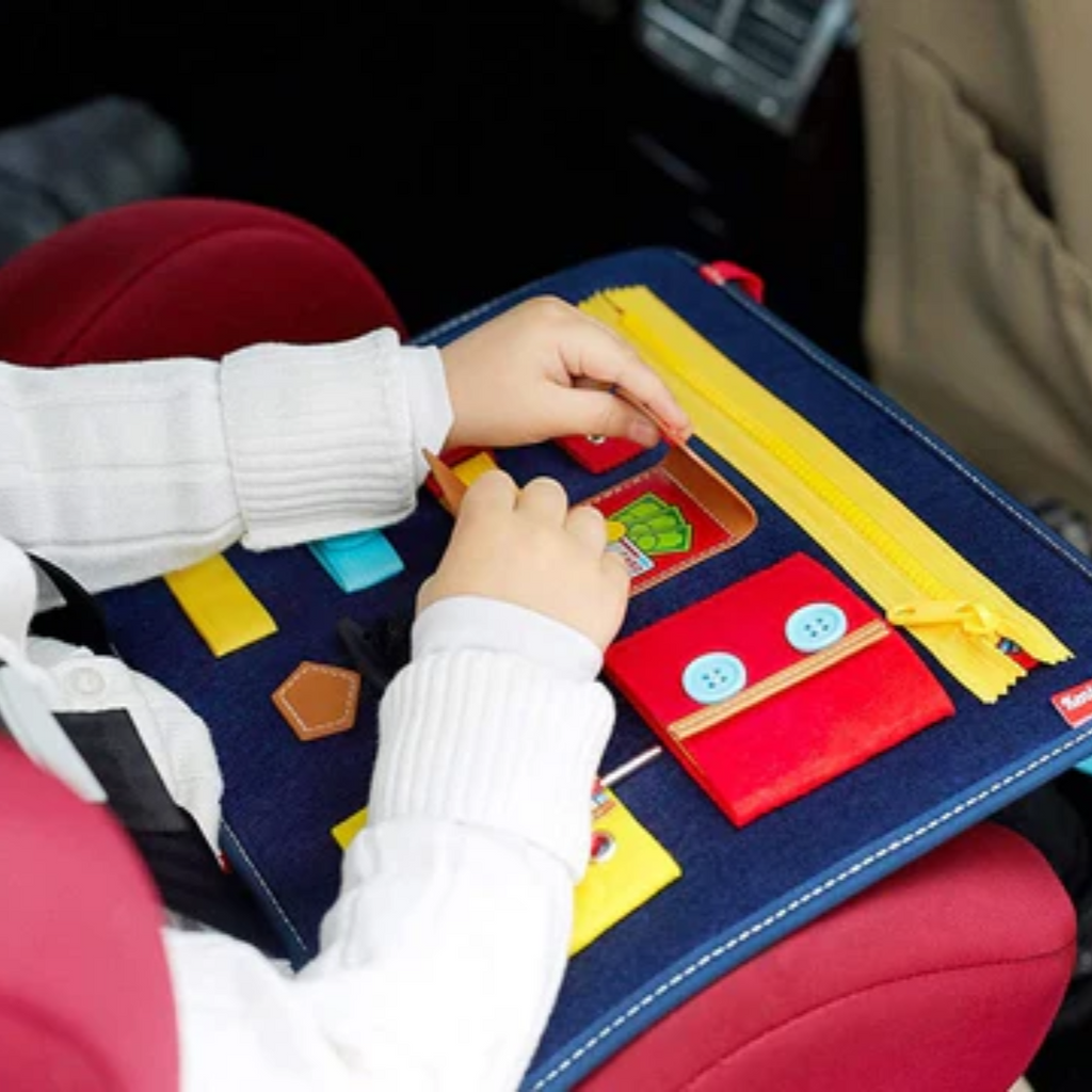 Niño concentrado manipulando las actividades del tablero Montessori durante un viaje