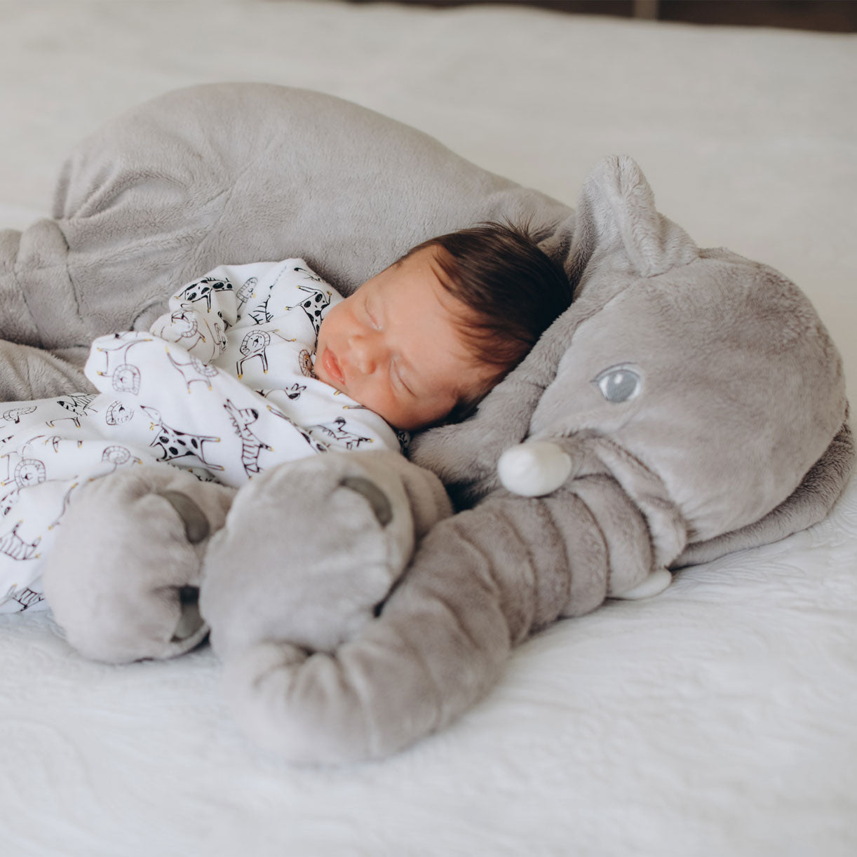 Cojín elefante azul de 60cm junto a bebé para comparación de tamaño