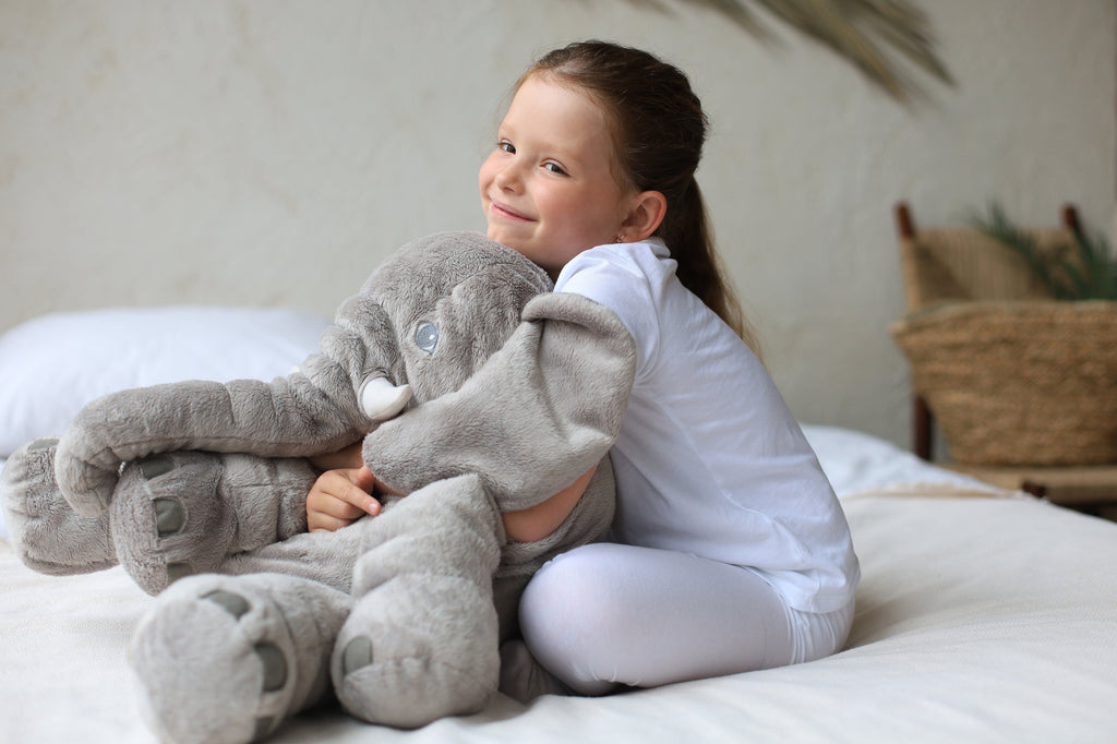 Cojín elefante amarillo usado como almohada decorativa en cuna