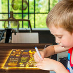 Niño utilizando la tableta LED iluminada para trazar dibujos y practicar letras con rotuladores borrables