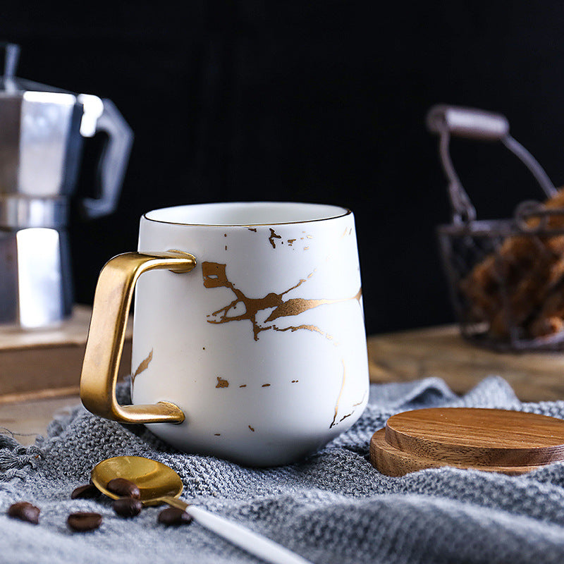 Taza de té y café de cerámica con diseño marmolado dorado y plato de madera